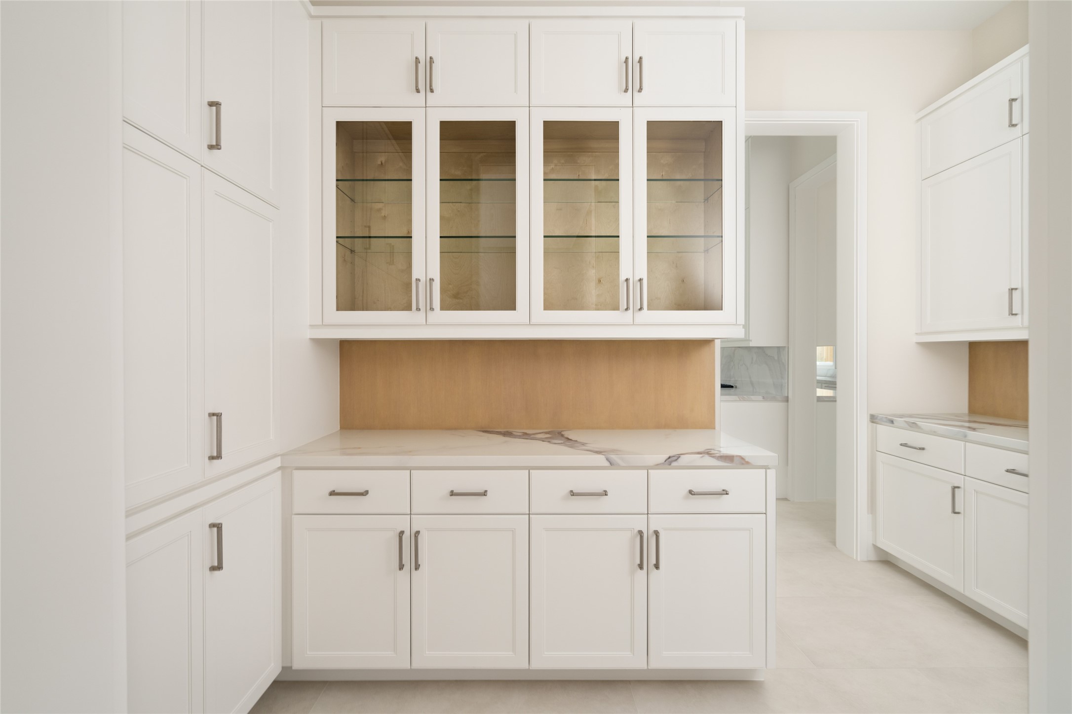 4006 Overbrook Lane Houston, TX 77027 - Photo 20 of 50 Elegant butler’s pantry featuring glass display cabinetry, quartzite surfaces, and built-in storage throughout.