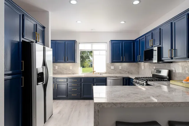 a kitchen with stainless steel appliances granite countertop a refrigerator and a stove top oven