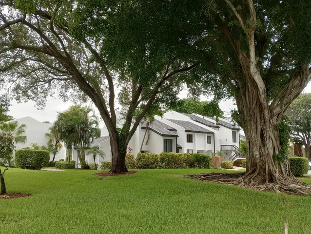 a front view of a house with a garden and tree