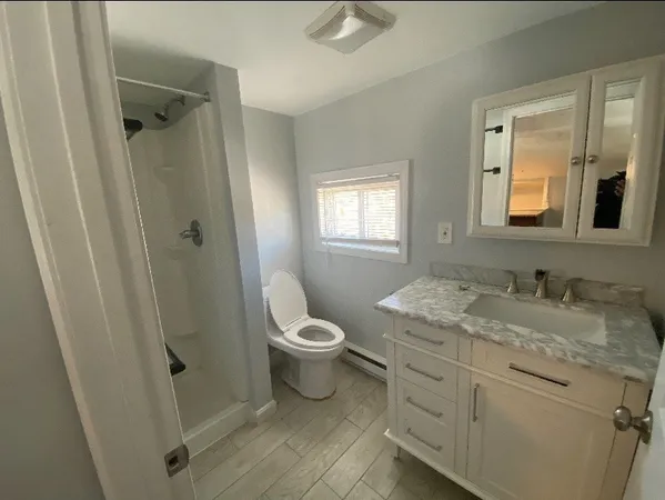 a bathroom with a granite countertop sink toilet and shower