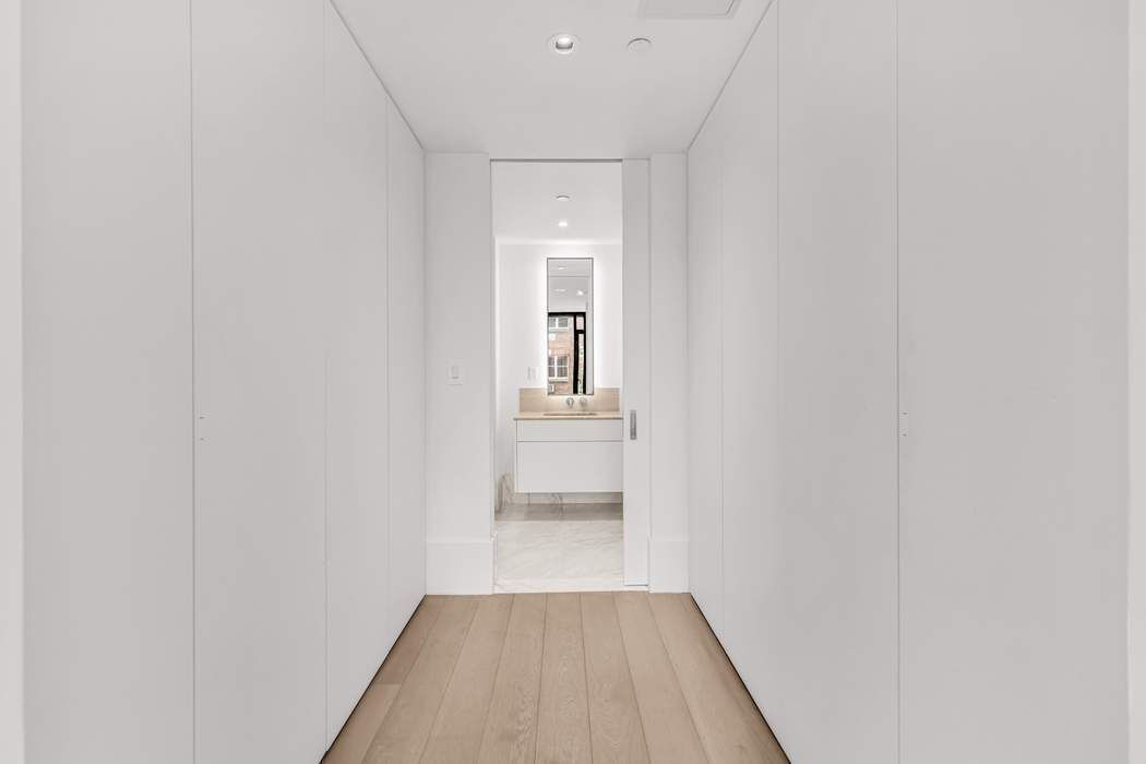 429 Kent Avenue, Unit 503 Brooklyn, NY 11249 - Photo 8 of 14 a view of a hallway with wooden floor and a bathroom