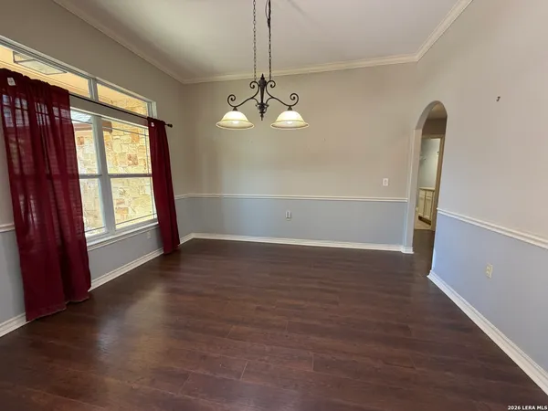 an empty room with wooden floor cabinet and windows