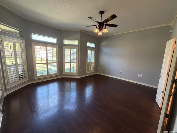 a view of an empty room with wooden floor and a window