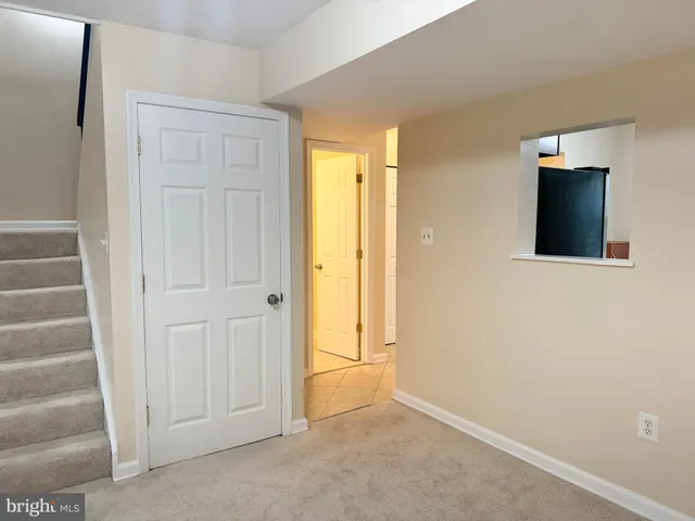 a view of an empty room with stairs and a closet