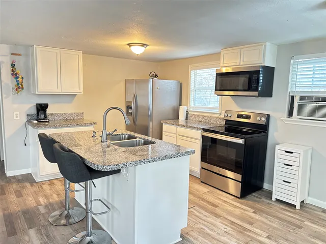 a kitchen with stainless steel appliances granite countertop a stove a sink and a microwave