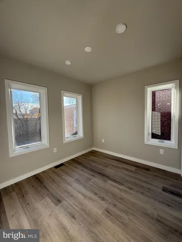 a view of an empty room with window and wooden floor