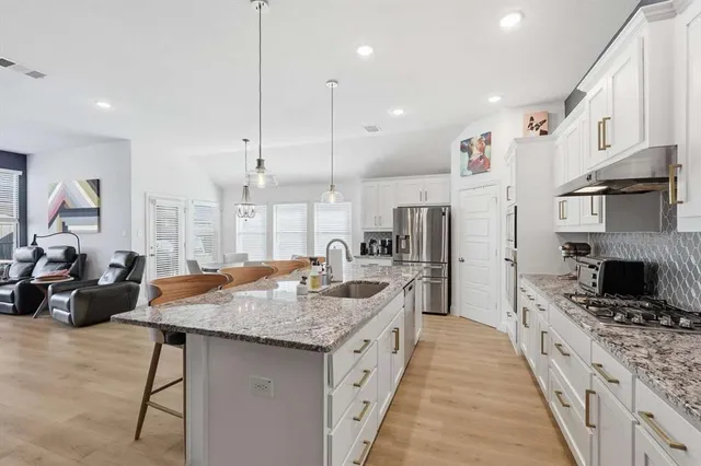 a kitchen with stainless steel appliances granite countertop a stove refrigerator a oven a sink with a dining table and chairs