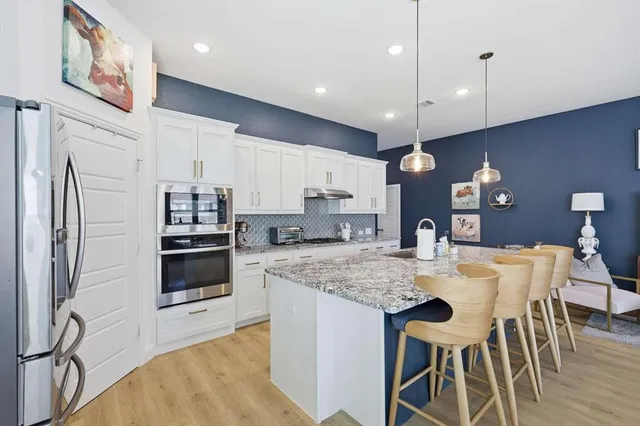 a large kitchen with stainless steel appliances kitchen island granite countertop a table chairs sink and cabinets