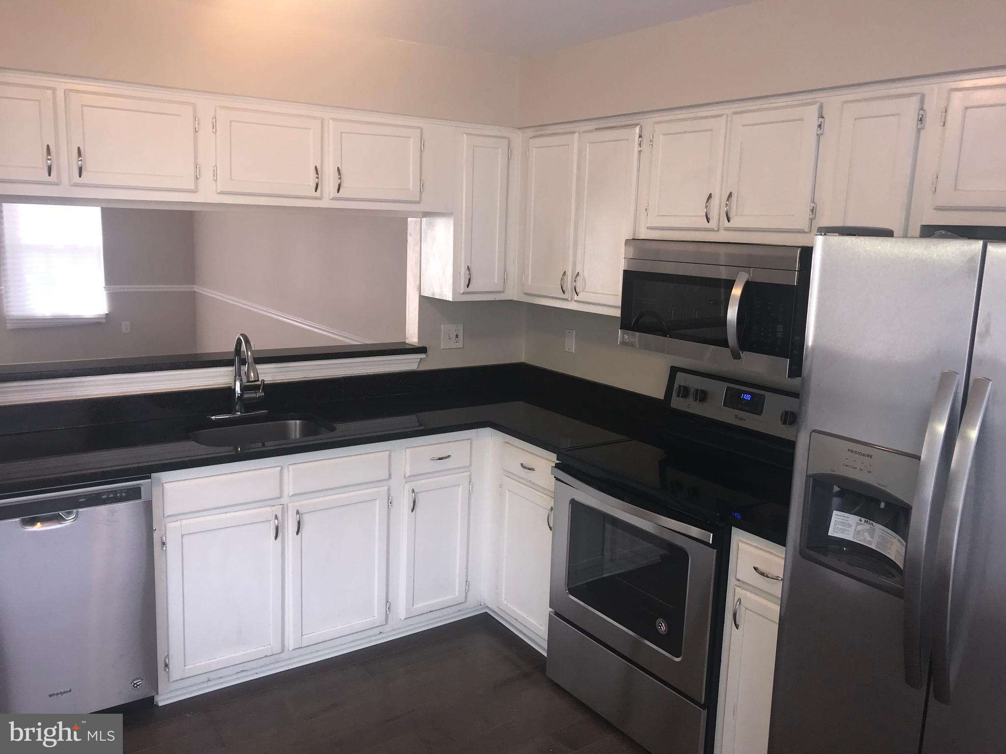 8657 Ritchboro Road District Heights, MD 20747 - Photo 3 of 23 a kitchen with granite countertop white cabinets and black appliances