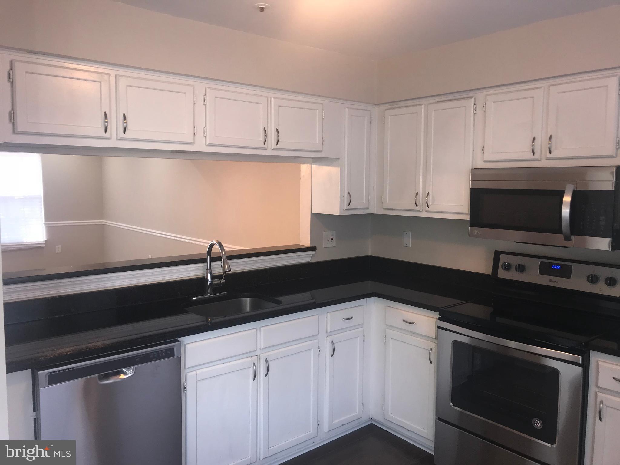 8657 Ritchboro Road District Heights, MD 20747 - Photo 5 of 23 a kitchen with granite countertop white cabinets and black appliances