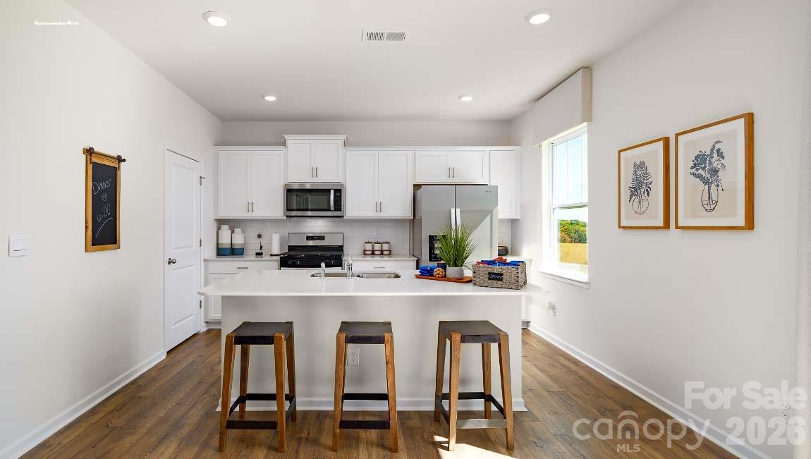 602 Dazzle Loop Newton, NC 28658 - Photo 5 of 29 a kitchen with stainless steel appliances a microwave a stove a refrigerator a stove a dining table and chairs with wooden floor