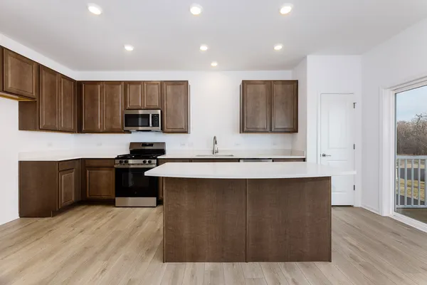 a kitchen with stainless steel appliances a sink a stove a microwave a center island and cabinets