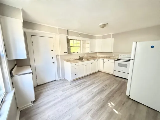 a kitchen with a sink a refrigerator a stove and wooden floor