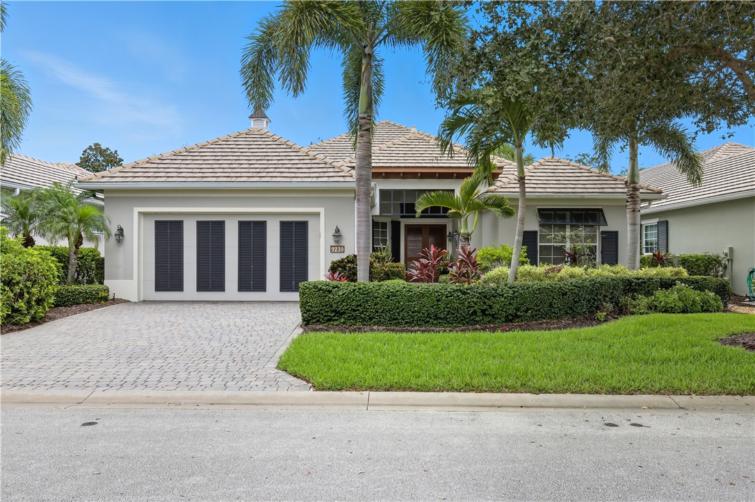 a front view of a house with a garden and palm trees