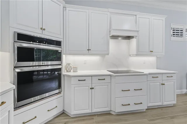 a kitchen with granite countertop white cabinets and stainless steel appliances