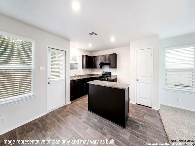 a kitchen with granite countertop a refrigerator stove and sink