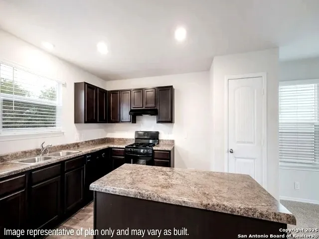 a kitchen with granite countertop kitchen island stainless steel appliances a sink stove top oven and granite counter tops