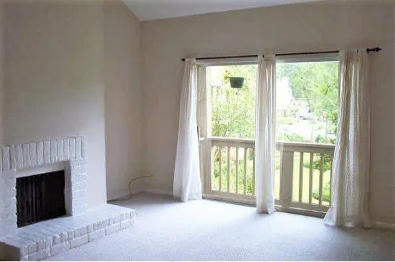 a view of an empty room with a fireplace and a window