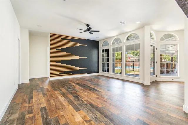 a view of an empty room with a window and wooden floor