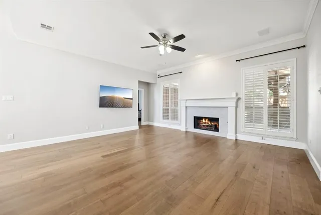 a view of an empty room with wooden floor fireplace and a window