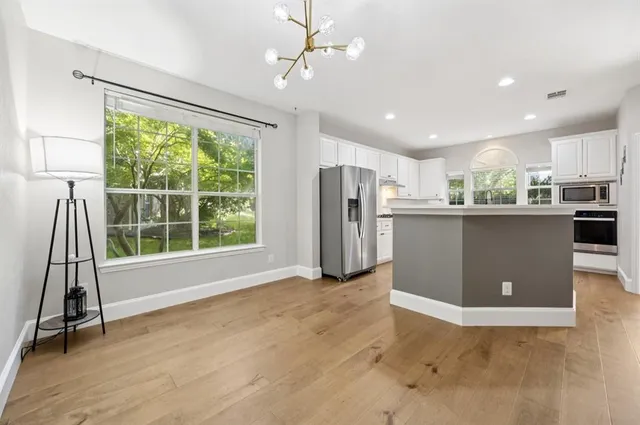 a view of a kitchen with refrigerator and wooden floor