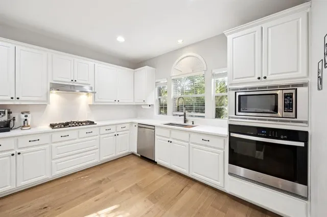 a kitchen with white cabinets stainless steel appliances and sink