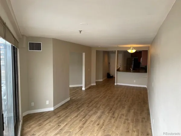 a view of a big room with wooden floor and a window