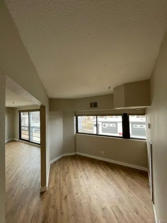 an empty room with wooden floor and windows