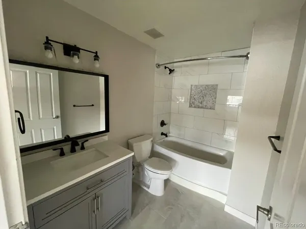 a bathroom with a bathtub shower sink vanity and toilet