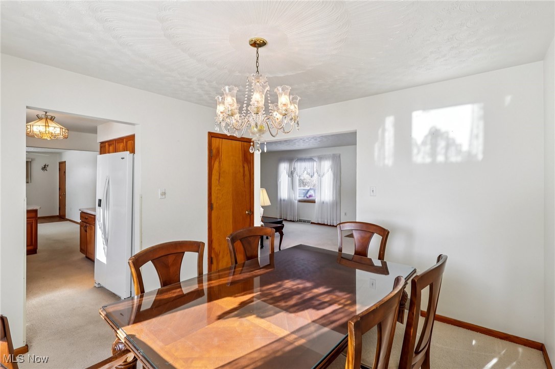 970 Eastern Road Doylestown, OH 44230 - Photo 6 of 49 Dining room featuring light carpet, a chandelier, and a textured ceiling