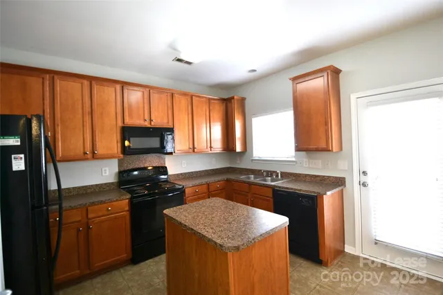 a kitchen with granite countertop a refrigerator stove and sink