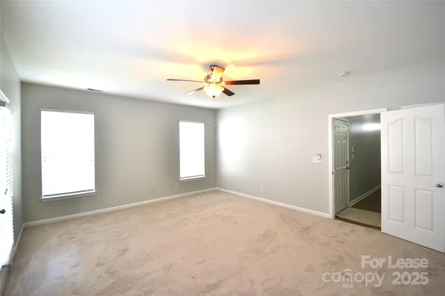 an empty room with windows and a ceiling fan