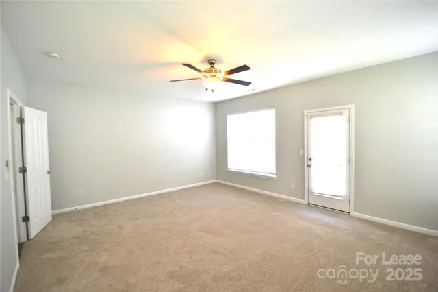 an empty room with windows and a ceiling fan