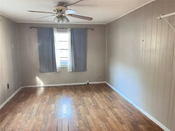 an empty room with wooden floor chandelier fan and windows