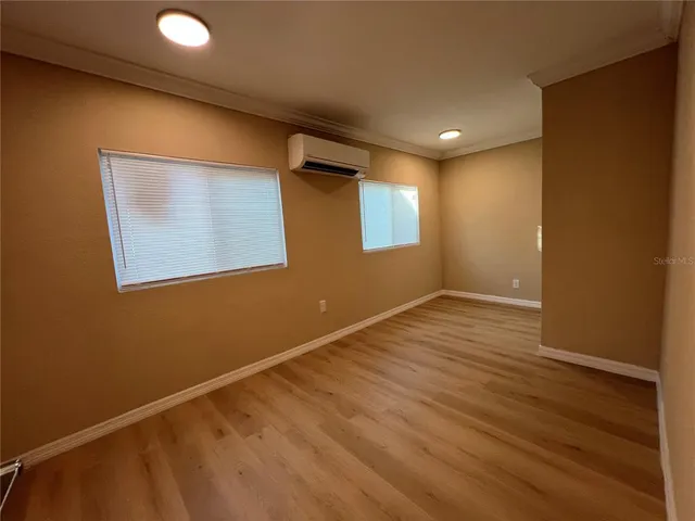 a view of an empty room with wooden floor and a window