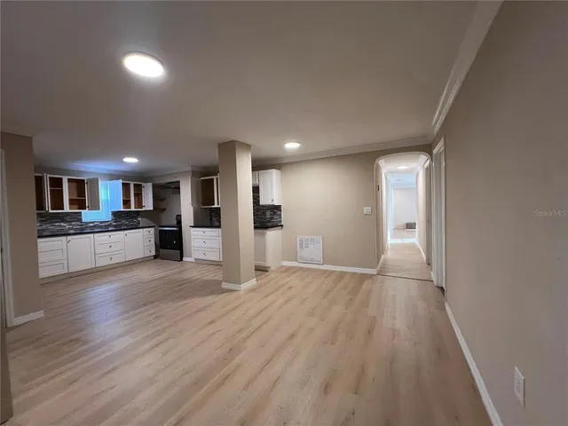 a view of a big room with wooden floor and a kitchen