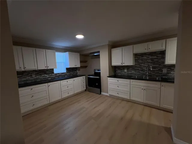 a kitchen with granite countertop white cabinets and stainless steel appliances