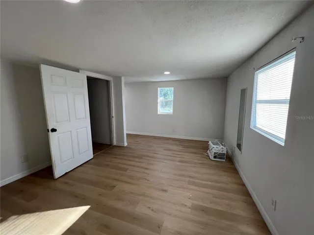 a view of an empty room with wooden floor and a window