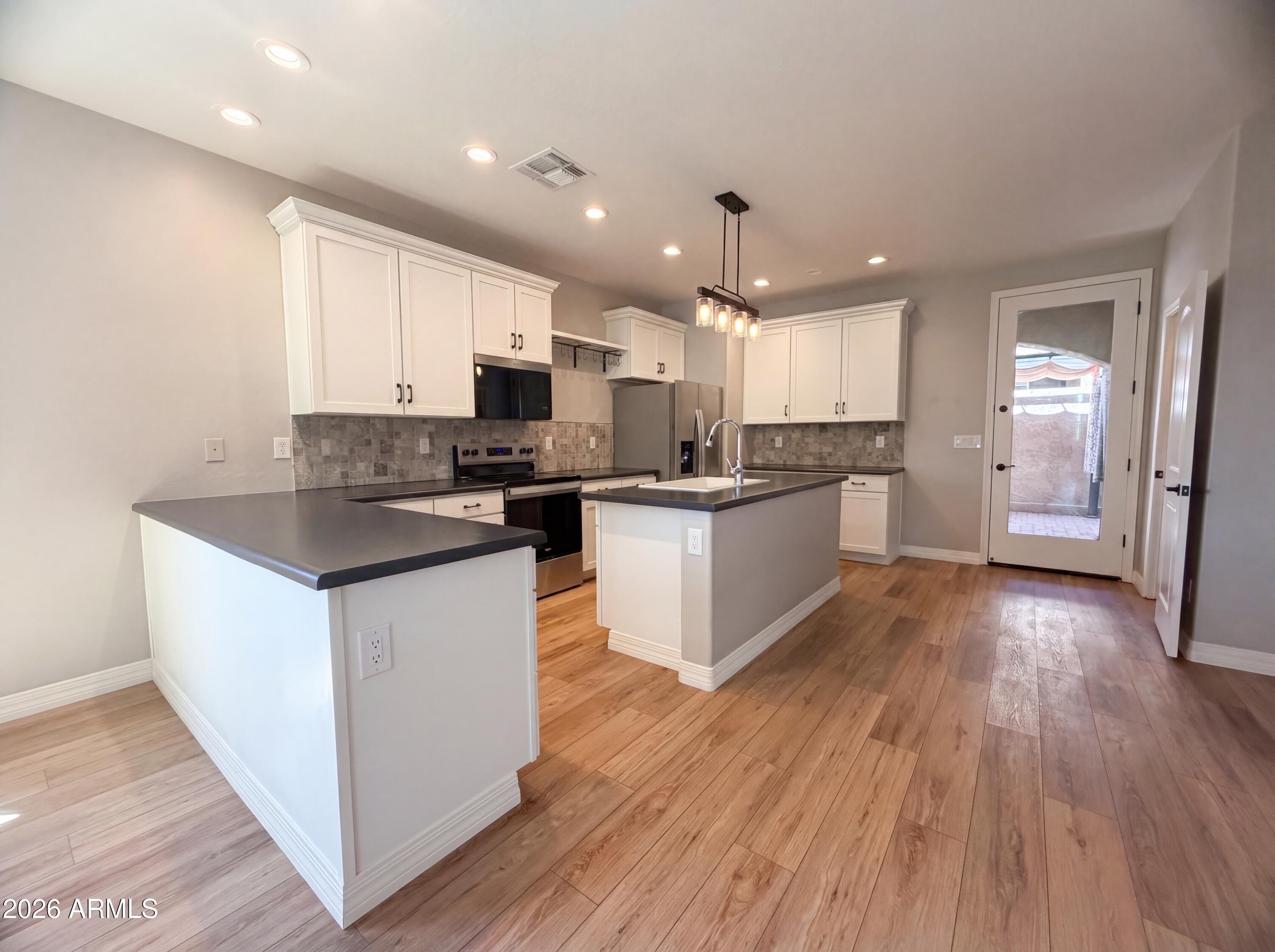 1729 South Desert View Place Apache Junction, AZ 85120 - Photo 2 of 17 a kitchen with stainless steel appliances kitchen island granite countertop wooden floors and white cabinets