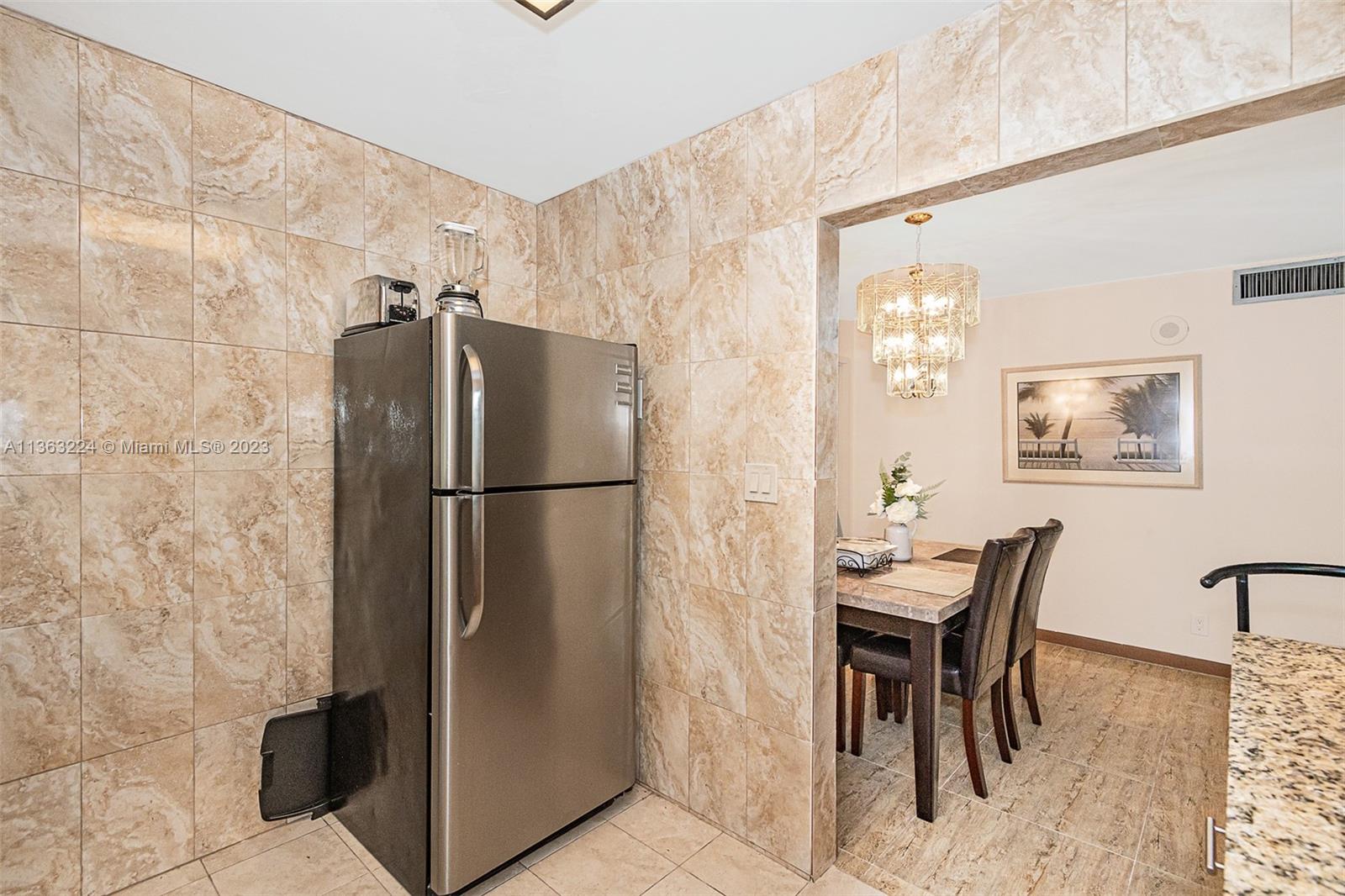 17011 North Bay Road, Unit 107 Sunny Isles Beach, FL 33160 - Photo 16 of 26 a kitchen with stainless steel appliances refrigerator dining table and chairs