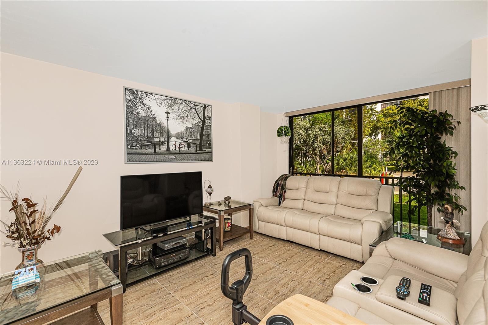 17011 North Bay Road, Unit 107 Sunny Isles Beach, FL 33160 - Photo 9 of 26 a living room with furniture a flat screen tv and a floor to ceiling window