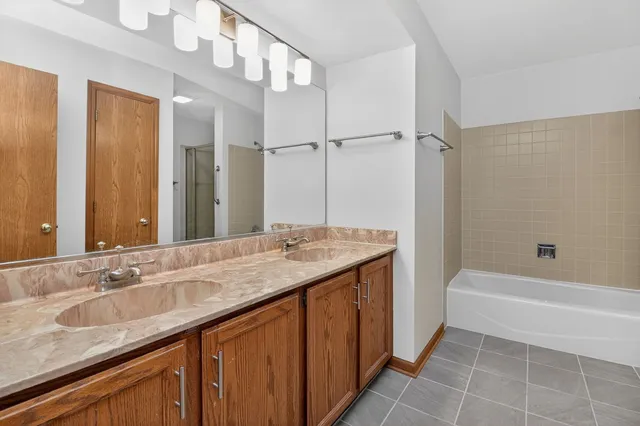 a bathroom with a granite countertop sink a mirror and a bathtub