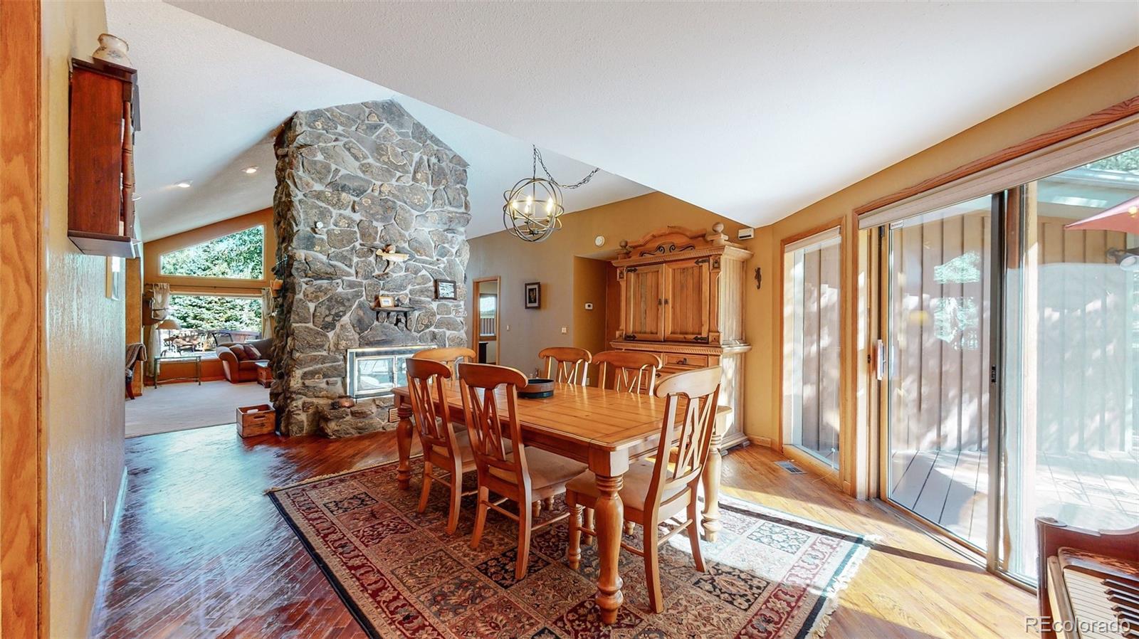 2720 South Spring Gulch Road Idaho Springs, CO 80452 - Photo 7 of 38 a view of a dining room with furniture wooden floor and a floor to ceiling window