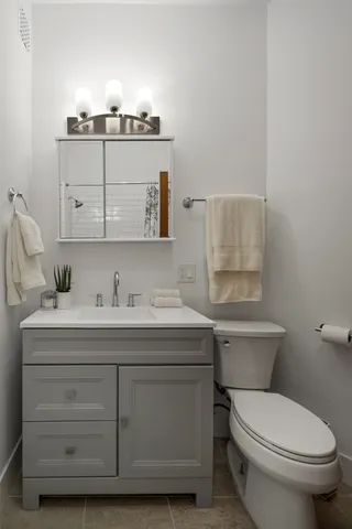 a bathroom with a granite countertop toilet sink and mirror