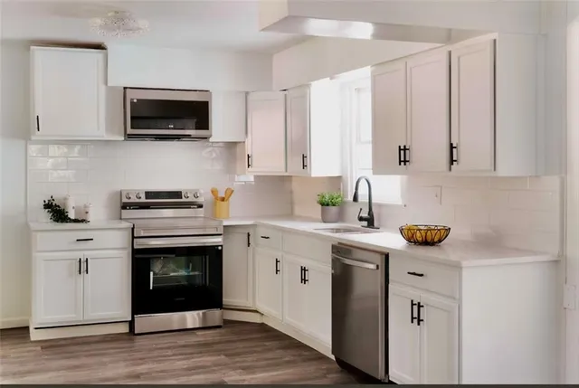 a kitchen with cabinets stainless steel appliances a sink and wooden floor