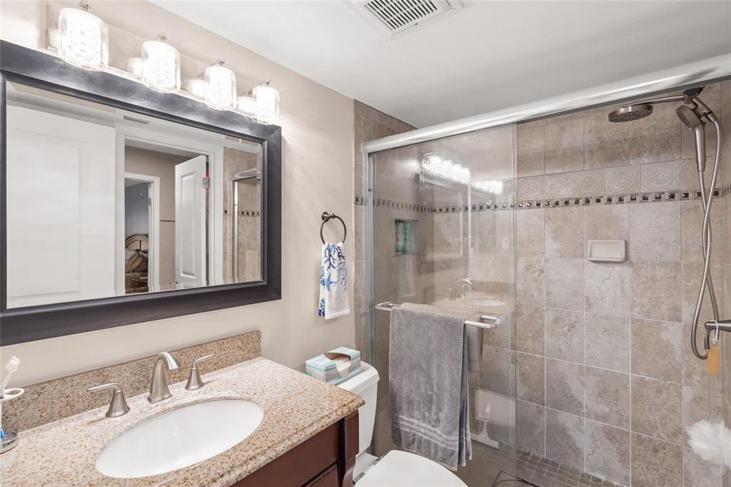 1630 Stickney Point Road, Unit 101 Sarasota, FL 34231 - Photo 19 of 40 a bathroom with a granite countertop shower sink and mirror