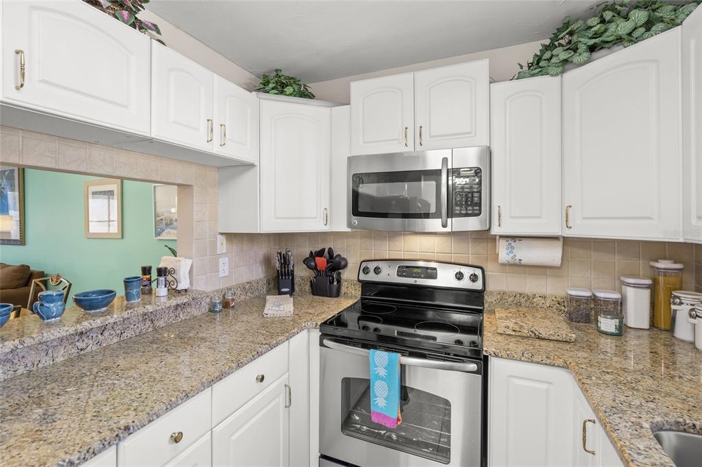 1630 Stickney Point Road, Unit 101 Sarasota, FL 34231 - Photo 5 of 40 a kitchen with stainless steel appliances granite countertop a stove a sink and a microwave