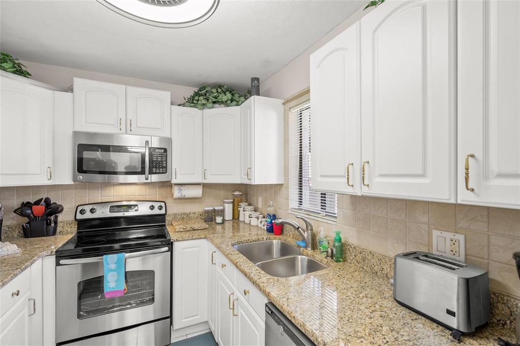 1630 Stickney Point Road, Unit 101 Sarasota, FL 34231 - Photo 6 of 40 a kitchen with stainless steel appliances granite countertop a sink a stove a microwave and cabinets