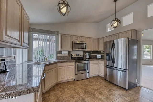 a kitchen with stainless steel appliances granite countertop a refrigerator a stove a sink and dishwasher