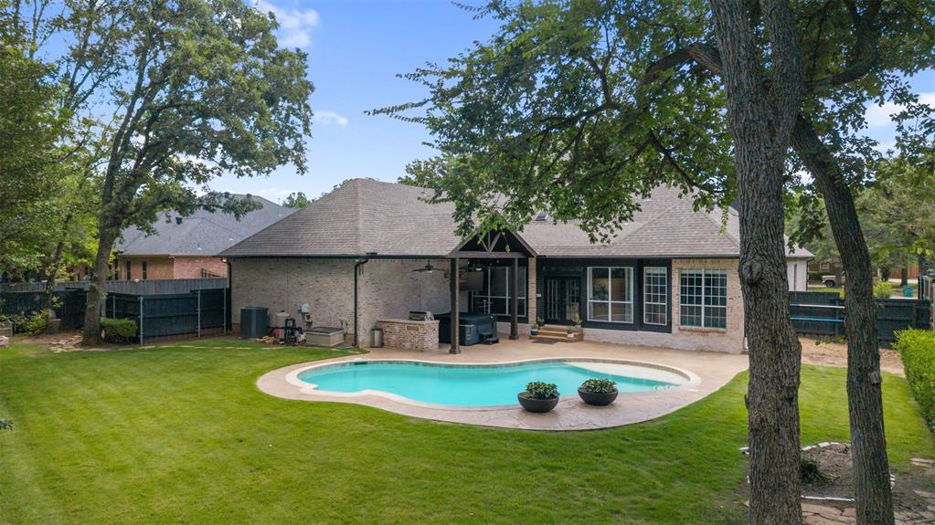 609 Seville Road Denton, TX 76205 - Photo 6 of 40 Spacious grassy backyard with lots of trees, pool and outdoor living center.